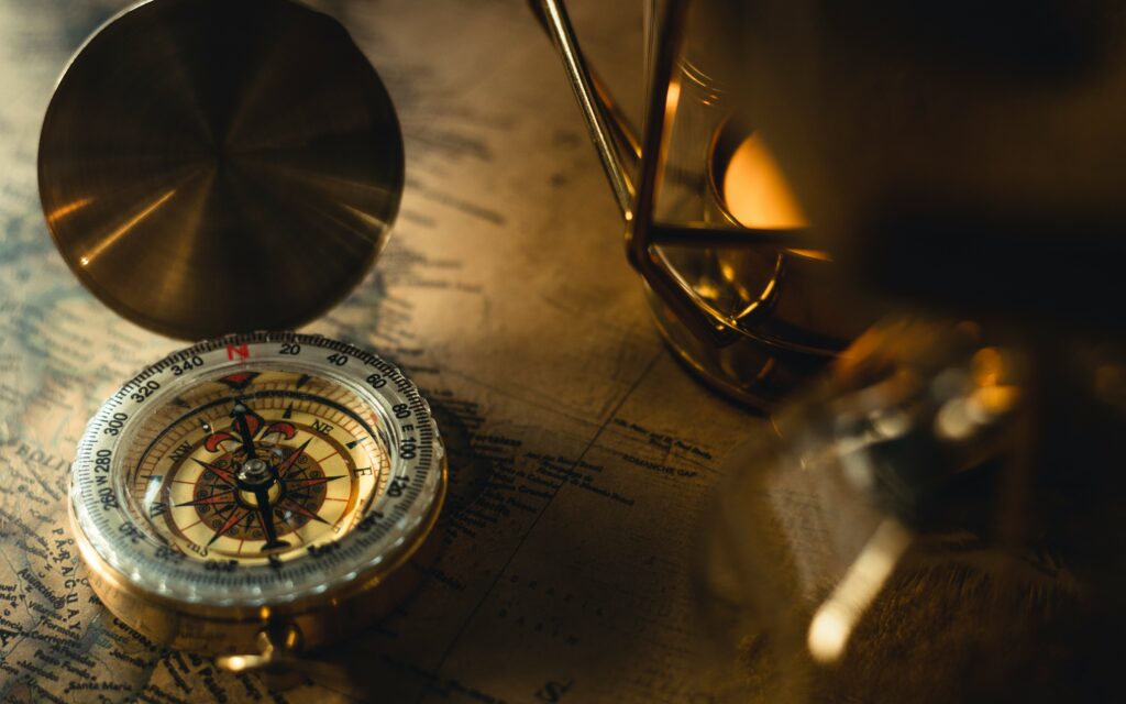 A compass, a globe and other navigational implements, overlaying a chart, exemplifying the main themes of  maritime adventure, historical gothic maritime exploration  and found identity present in Morgan A. Drake paranormal fiction.
