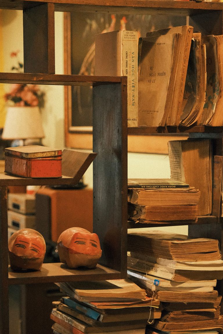 An antique bookshelf filled with dusty books and wooden masks, evoking nostalgia. Cover for Morgan A. Drake pen name disambiguation article.